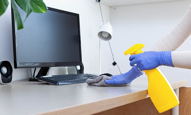 office desk being cleaned with a spray bottle and cloth